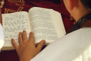 Young boy with a sidur preparing for his bar mitzvah