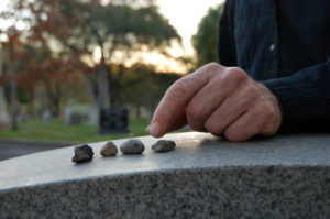 hand placing stones on a headstone